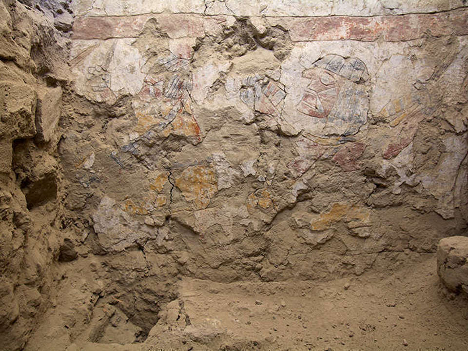 Two seated women display colorful threads and spinning or weaving tools in the lower part of an inner wall