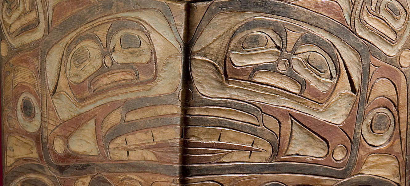 Close up of a Northwest Coast Native American carved wooden box with faded red and black paint