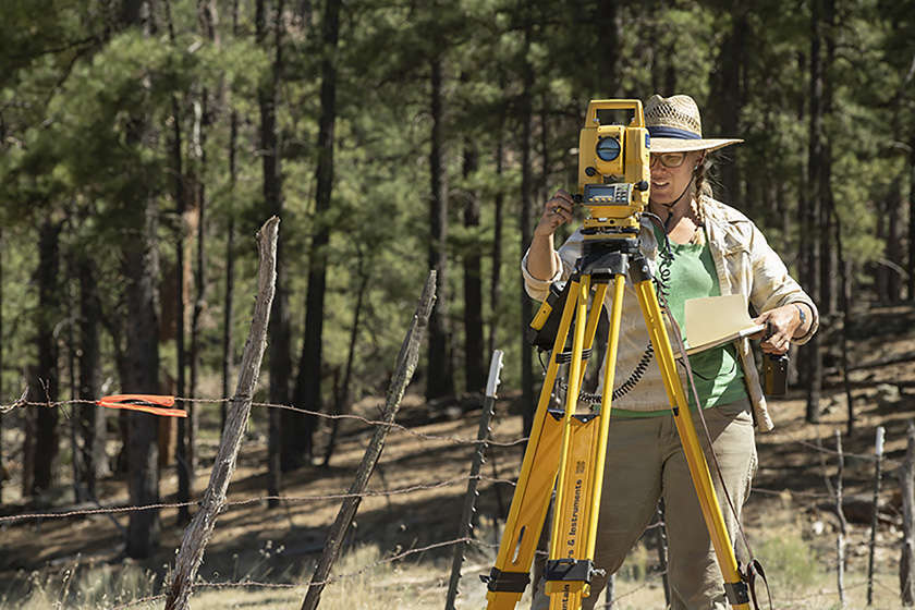 Three people using tools to excavate a paleontological site
