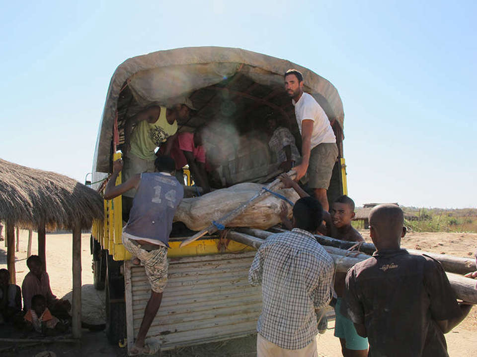 The back of an open truck with field jackets being loaded in by a large group of people