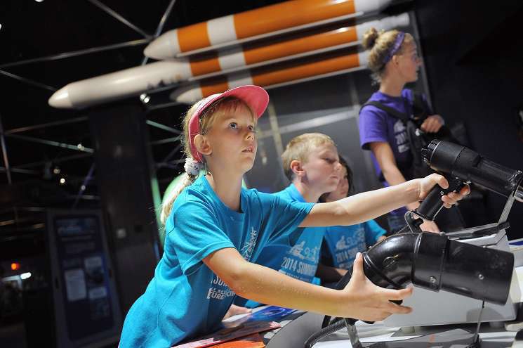 A young girl is seen playing with a rocket in Space Odyssey, highlighting her enthusiasm for science and discovery.