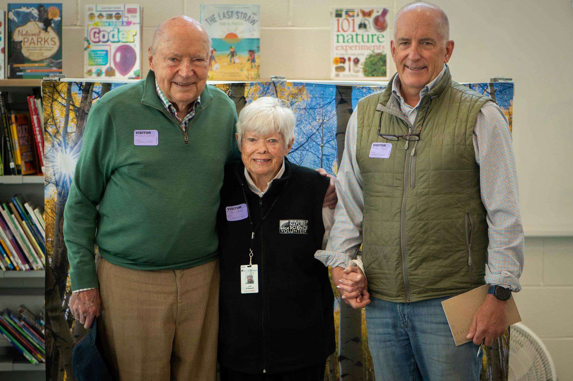 Ann O’Donnell, her husband, Canton O’Donnell and her son John O’Donnell at Granby Elementary School in front of a forest backdrop used in the Wonder Workshop they helped fund. (Photo/ Jordan Cooper)