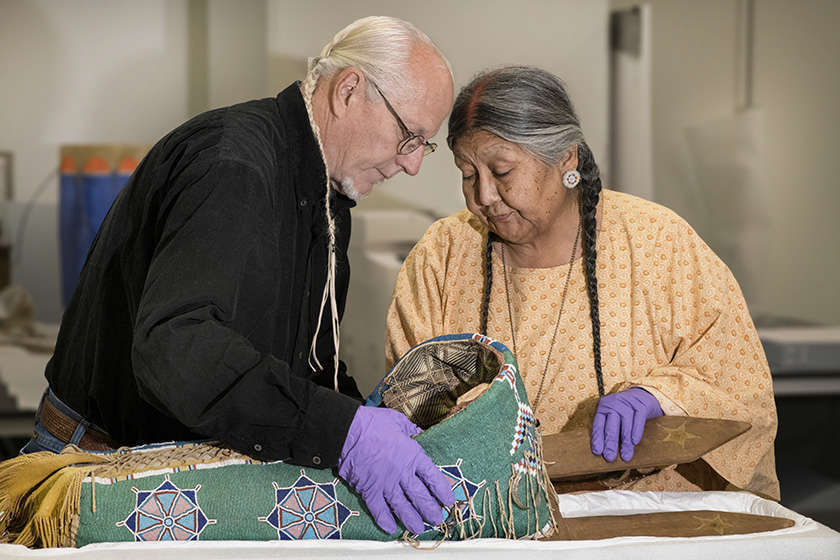Two elders examine a cradleboard