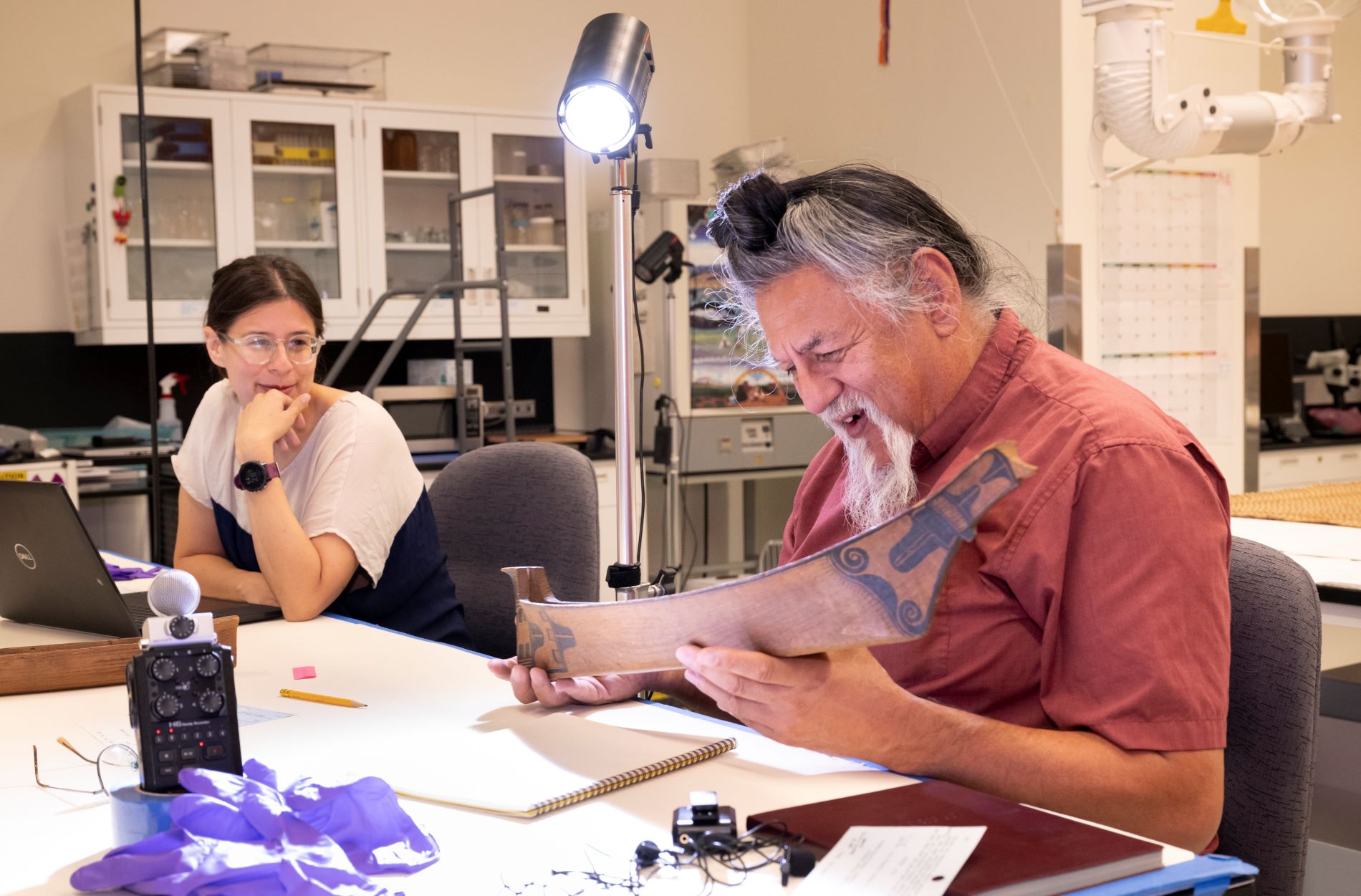 Ḥaa’yuups, Head of the House of Takiishtakamlthat-h, Tlikuulthat-h Clan, Huupa'chesat-h First Nation examined a carved model whaling canoe with Objects Conservator Katy Kaspari on October 2023 (Photo/ Rick Wicker)