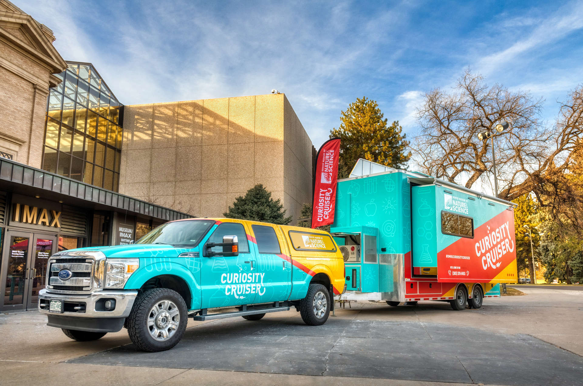 A colorful pickup truck and trailer with the Museum's Curiosity Cruiser branding