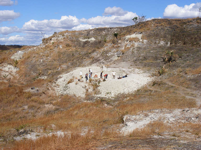 a far-away shot of the field site, with a group of people doing work on the site in the distance
