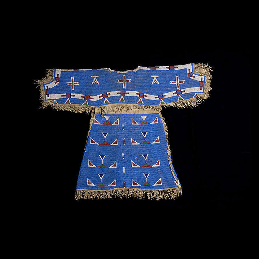 Blue, white and red beaded dress with leather fringe laid out on a black background